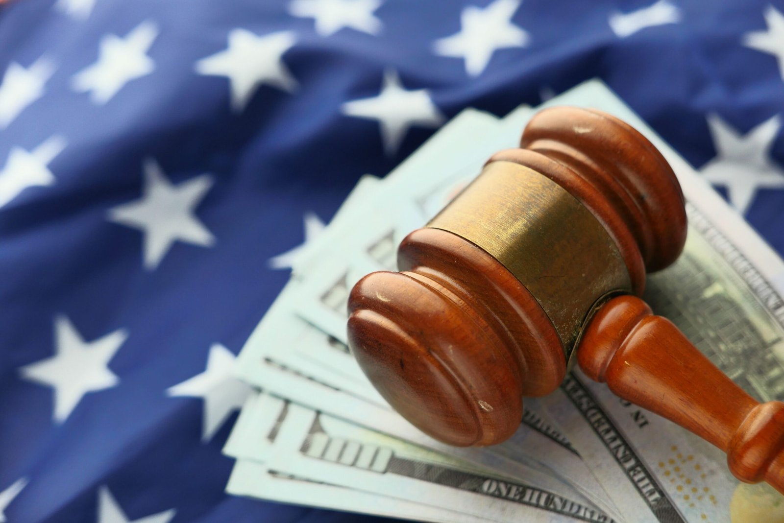 Contacto Close-up of a gavel on US dollar bills with American flag backdrop symbolizing justice and finance.